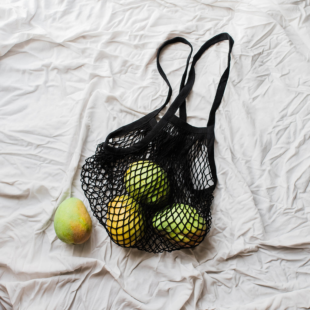 black fisherman basket holding green mangoes
