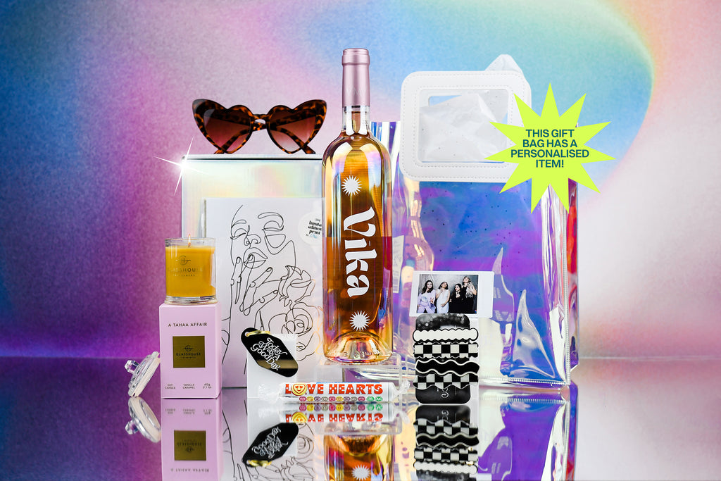 gift bag and contents, heart shaped sunglasses, personalised bottle of rose, glasshouse fragrance candle, gold foil a5 art print, motel keyring that says today was a good day, love hearts candy, polaroid photo of 4 girls, a pack of 4 black and white geometric print hair clips