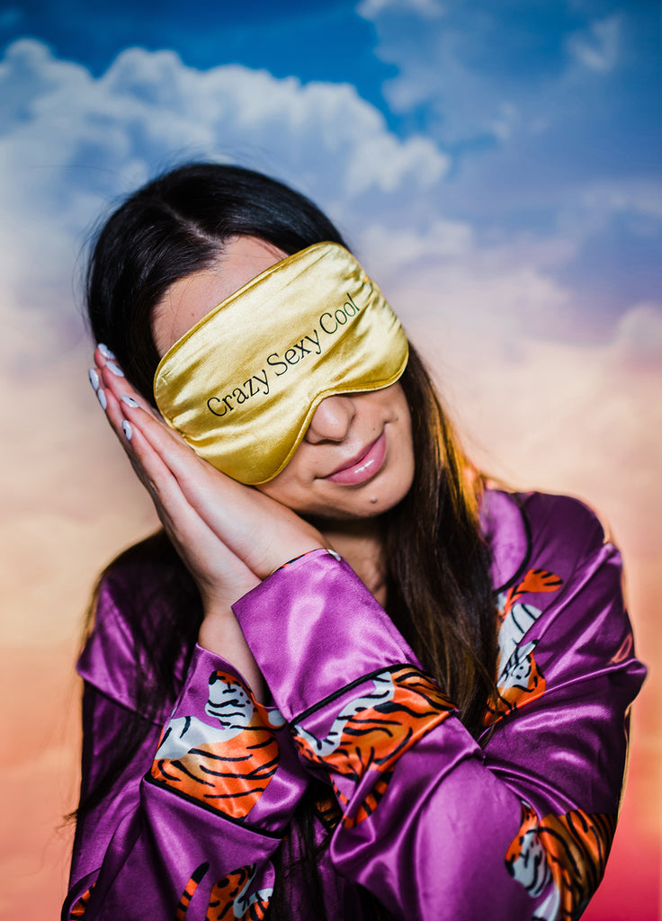 girl in pink silk pyjamas with tigers wearing gold silk face mask that reads crazy sexy cool