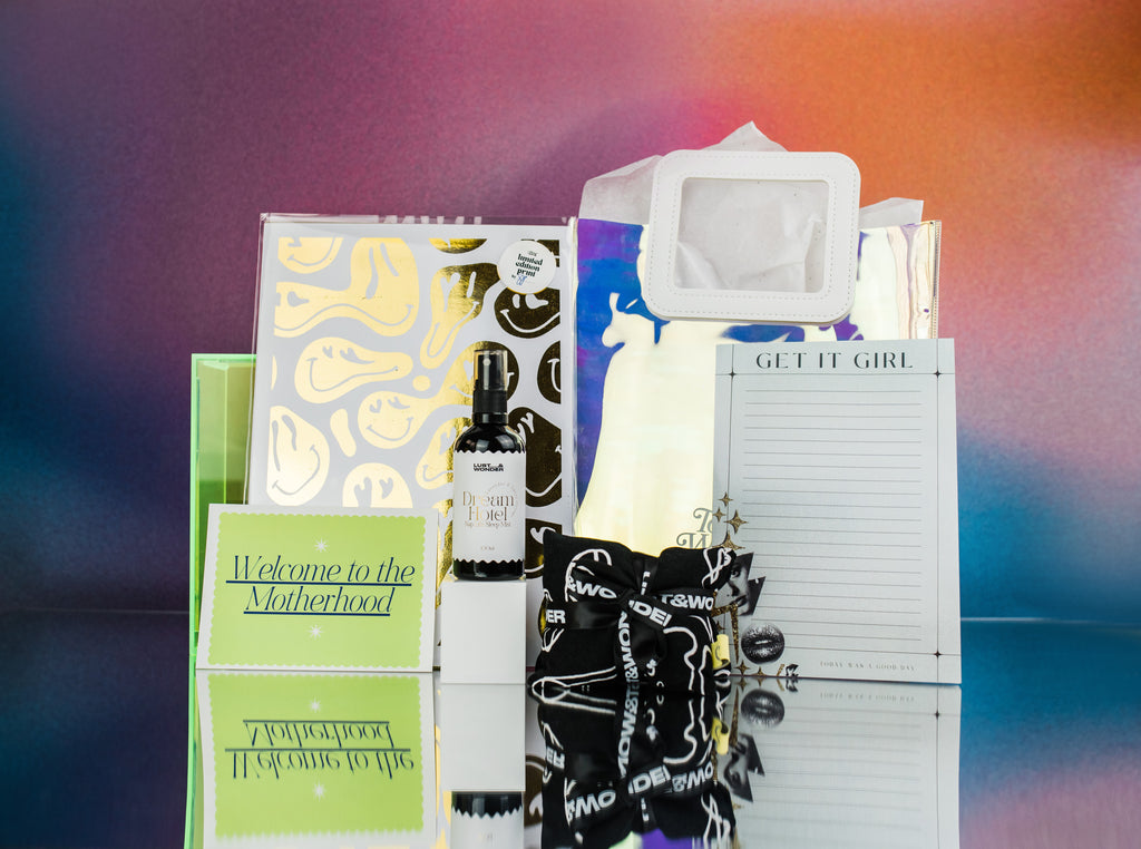gift bag and its contents, gold foil art print melted smiley faces, room spay Dream hotel by lust and wonder, get it girl notepad, black and white heat pack by lust and wonder, gift card