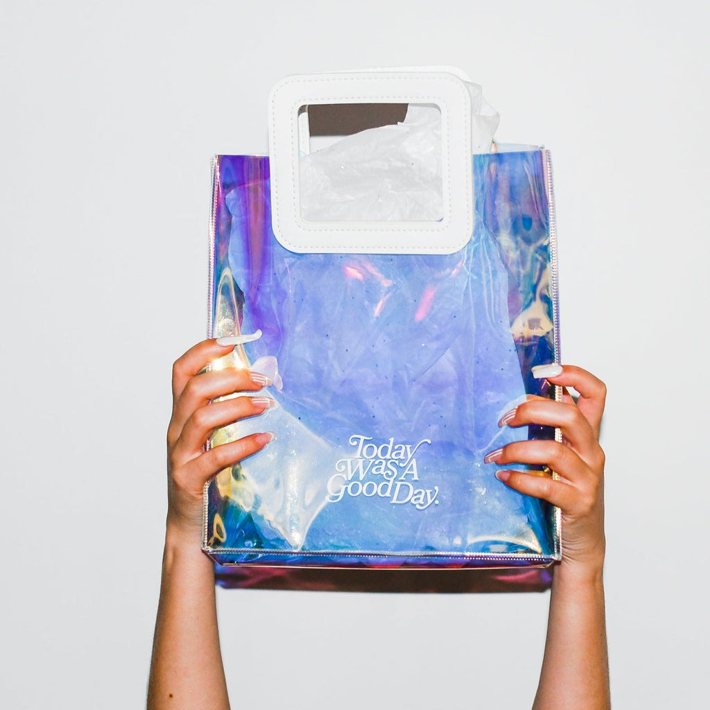two hands with cool manicure holding up a holographic carrier which states 'Today was a good day'