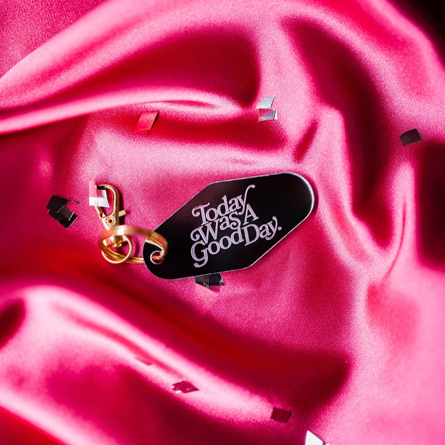 motel keyring mirrored etched with Today was a good day, over pink silk background